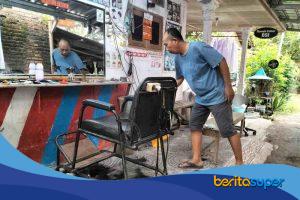 Sukardi, tukang cukur di Pangkas Rambut BSI Bojongsari Indramayu, sedang mencukur pelanggan di tempat usaha sederhana miliknya.